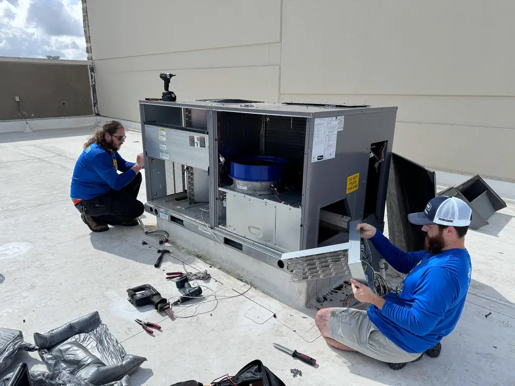 Two Air Monkey technicians servicing a rooftop packaged unit in Tomball, Texas