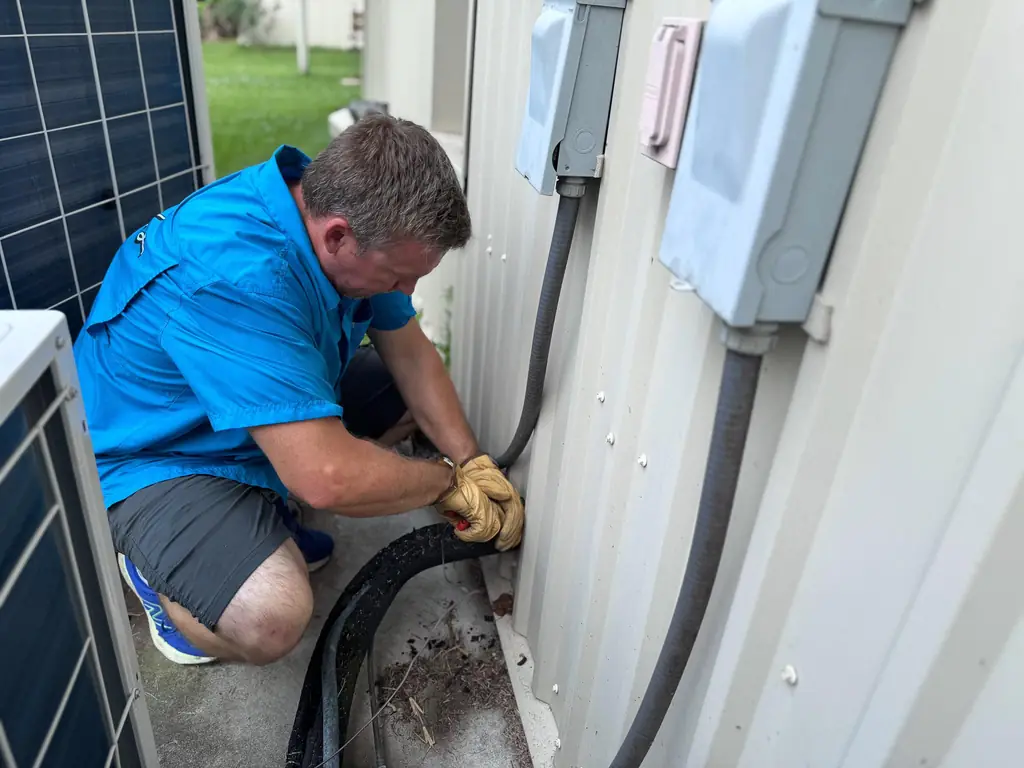 Air Monkey technician routing an electrical connection at a residential condenser in Tomball, TX