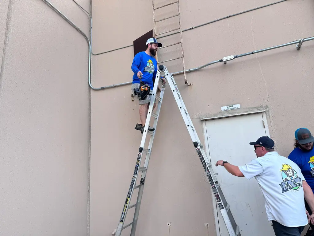 Three Air Monkey team members setting ladders for roof access on a commercial building